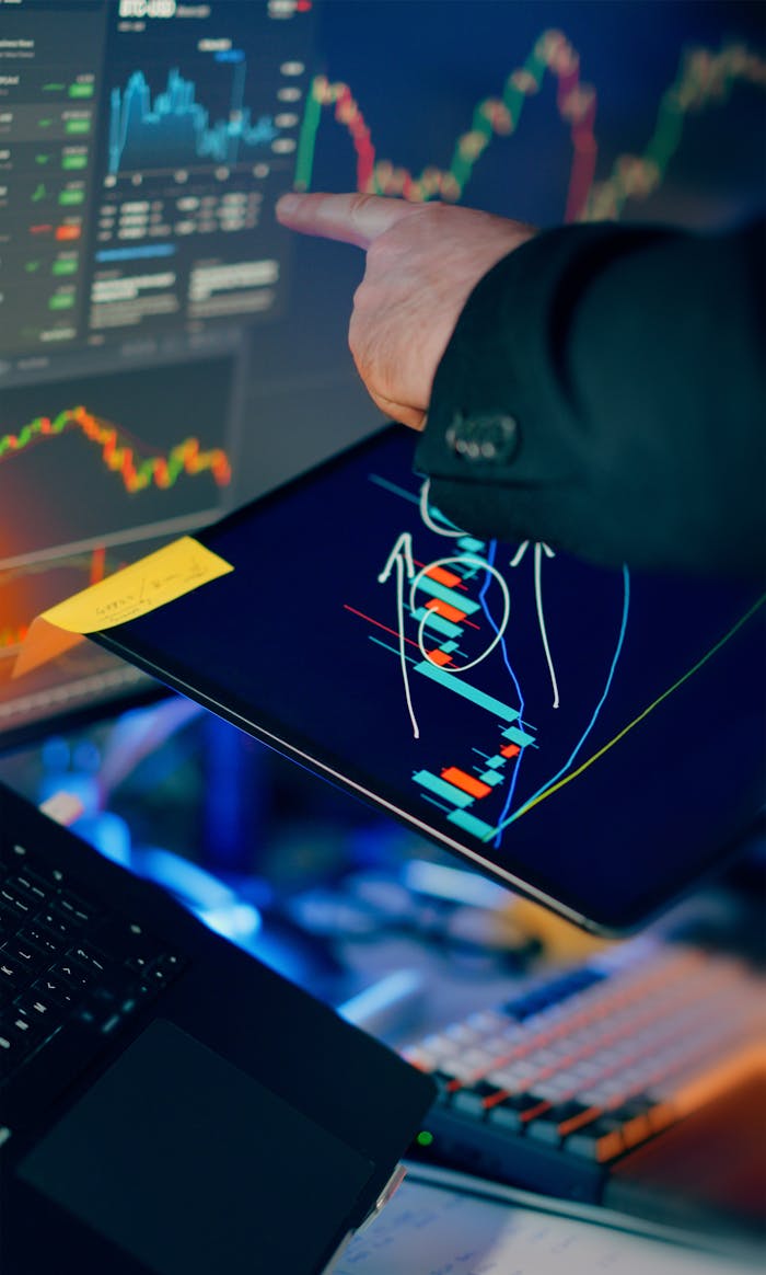 services-02 A business professional examines financial charts on a tablet and monitor for investment strategy.